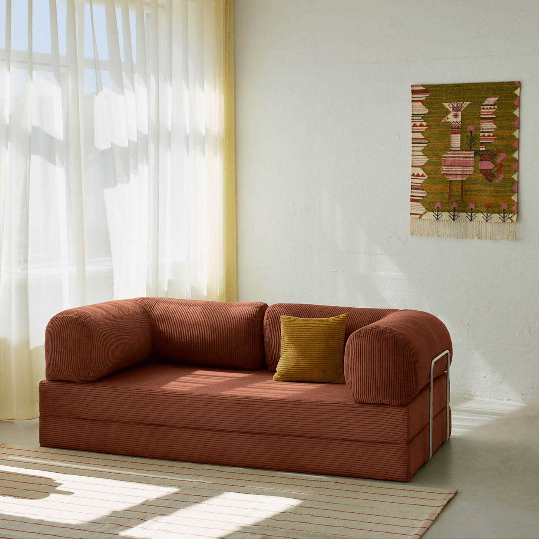 Primyhome brown corduroy convertible sofa bed in a sunlit living room with minimalist decor and boho wall art