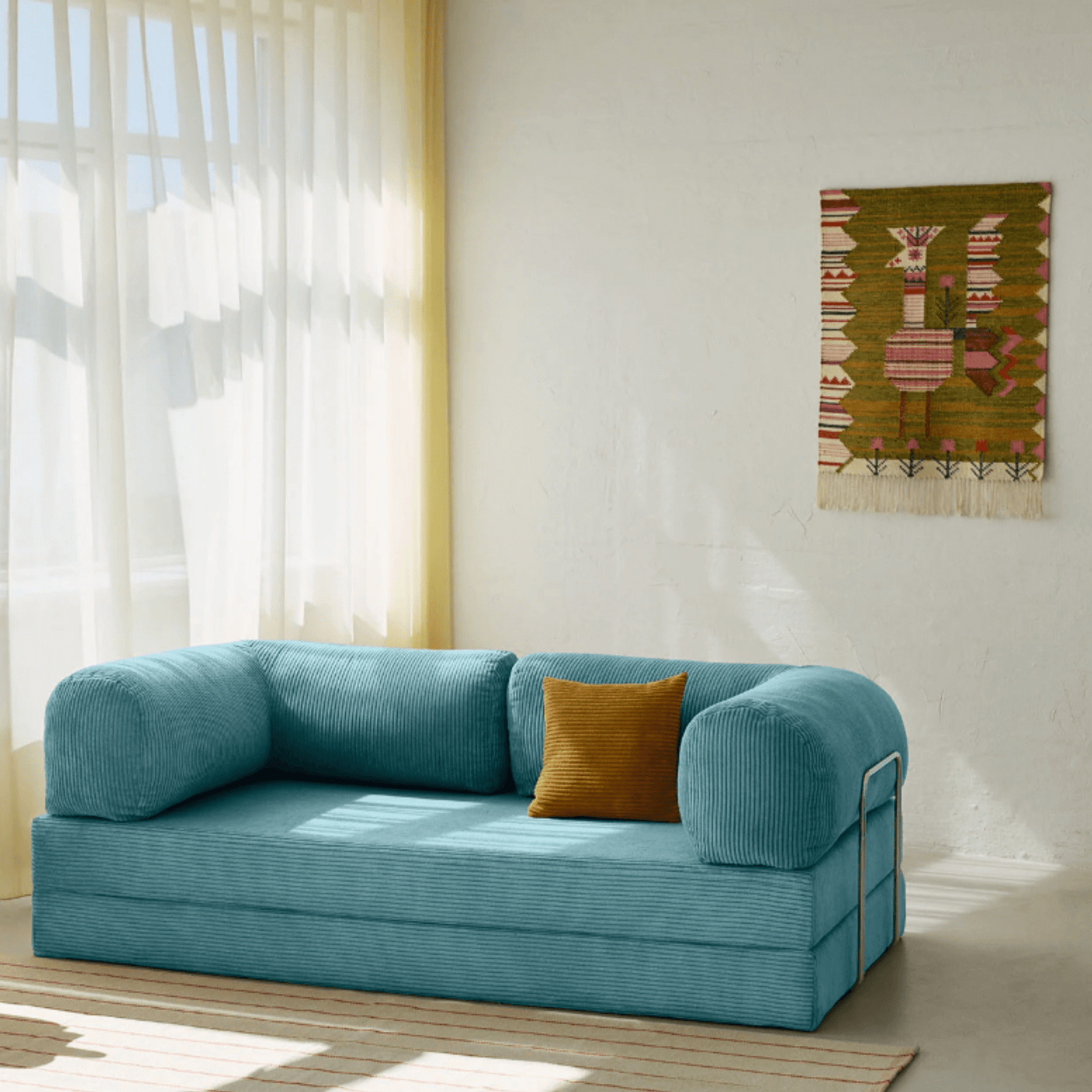Primyhome light blue corduroy convertible sofa bed in a sunlit living room with minimalist decor and boho wall art