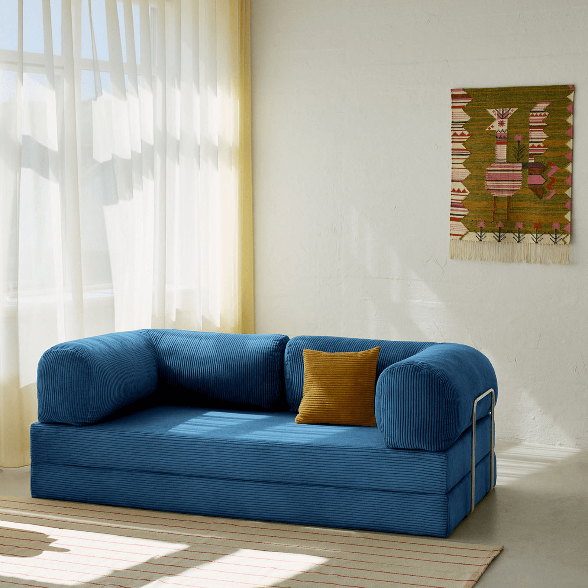 Primyhome navy blue corduroy convertible sofa bed in a sunlit living room with minimalist decor and boho wall art